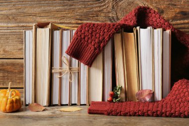 Farklı kitaplarla kompozisyon, kalın süveter ve ahşap masada sonbahar dekoru.