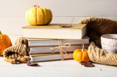 Kitap yığını, kalın kıyafetler, meşe palamudu ve balkabağı.