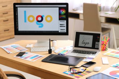 Ofiste modern bilgisayar, tablet, dizüstü bilgisayar ve renk paletleri ile grafik tasarımcılarının çalışma alanı