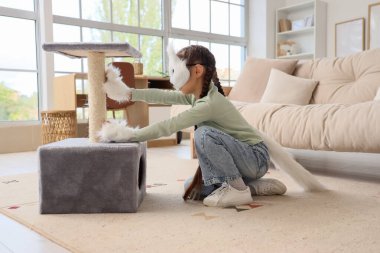 Evinde tırmalama tahtası olan kedi maskeli bir kız.