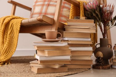 Odada koltuğun yanında çay fincanı olan kitap yığınları.