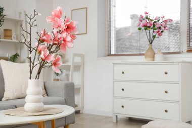 Oturma odasının içinde manolya çiçekleri olan kanepe ve kahve masası.