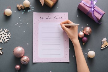 Karanlık arka planda Noel dekoru olan kadın yapılacaklar listesi yazıyor