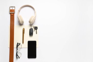 Modern kulaklıklı ve beyaz arka planda cep telefonlu şık erkek aksesuarları.