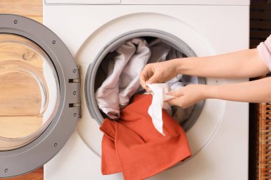 Kirli çamaşırları çamaşır makinesine atan kadın, yakın plan.