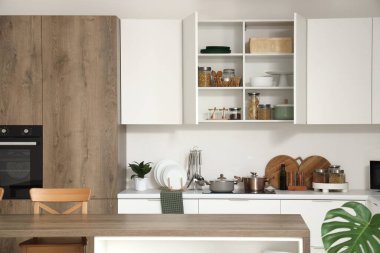 Mutfağın içi tezgah, dolap ve çatal bıçaklarla dolu.