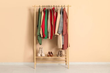 Soyunma odasındaki bej duvarın yanında şık sonbahar elbiseleriyle rafa kaldır.