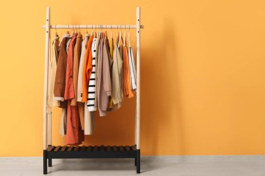 Sarı duvarın yanında sonbahar kıyafetleri asılı.