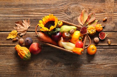 Tahta arka planda farklı taze sebzeler ve meyvelerle dolu bir sepet. Hasat festivali