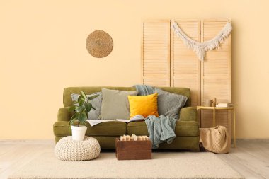 Koltuk, kahve masası, ev bitkisi ve kitap tutacağı.