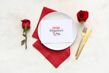 Kırmızı güllerle güzel masa ayarları ve beyaz arkaplanda Mutlu VALENTINE Günü yazılı tebrik kartı