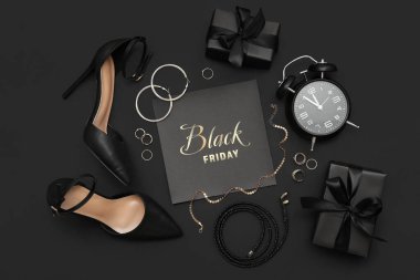 Siyah Cuma yazılı kart, şık bayan ayakkabıları, aksesuarlar ve koyu arkaplanda hediyeler