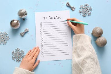 Mavi arka planda Noel dekoru olan kadın yapılacaklar listesi yazıyor