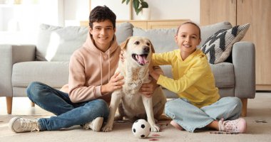 Şirin kız ve erkek kardeşleri ve şirin Labrador köpekleri evde yerde oturuyor.