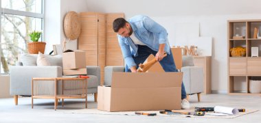 Genç adam evde mobilya montajı yapıyor.