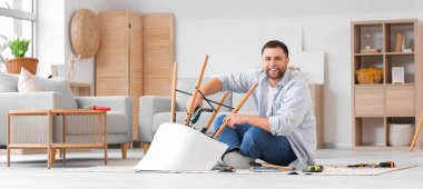 Young man with screwdriver assembling chair at home