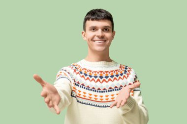 Yeşil arka planda işaret dilini kullanan genç sağır ve dilsiz adam.