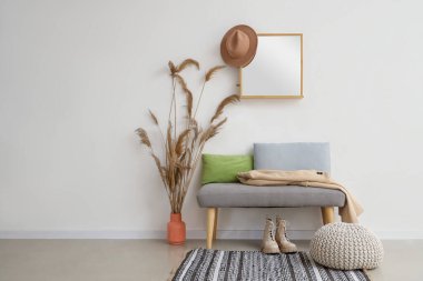 Salonun içinde yumuşak bank, ayna ve otlar var.