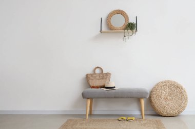 Salondaki ışık duvarının yanında yaz aksesuarları olan yumuşak bir bank.