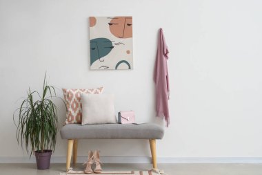 Salonun içinde yumuşak bank, palmiye ağacı ve resim var.