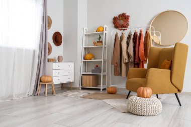 Palto askısı, koltuk ve balkabağı olan soyunma odasının içi.