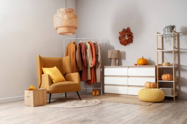 Koltuğu, balkabağı ve sonbahar kıyafetleri askıda asılı şık bir soyunma odası.