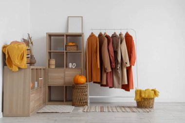 Ahşap rafları, balkabakları ve askıda asılı sonbahar kıyafetleri olan şık bir soyunma odası.