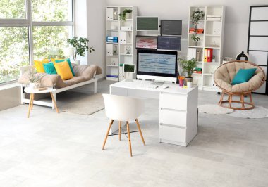 Masaları, raf üniteleri ve kanepesi olan ışık programcıları ofisinin içinde.