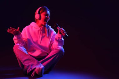 Koyu arka planda mikrofon ve kulaklıkları olan harika bir bayan şarkıcı.