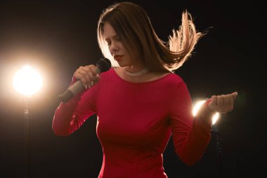 Koyu arka planda mikrofon ile güzel kadın şarkıcı