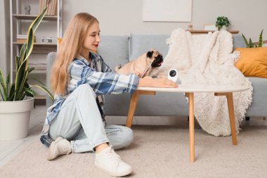 Genç bir kadın köpeğini izlemek için cep telefonu kullanıyor.