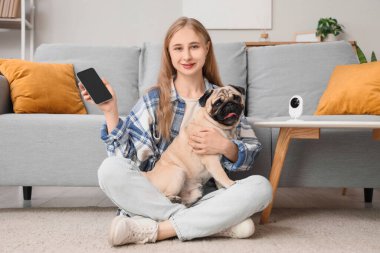 Evde cep telefonu kullanan pug dog ve CCTV kameralı genç bir kadın.