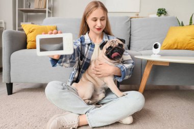 Evde video monitörü ve köpekli genç bir kadın var.