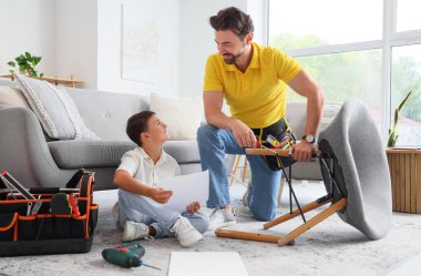 Babası ve küçük oğlu talimatlarla evde iskemle monte ediyorlar.