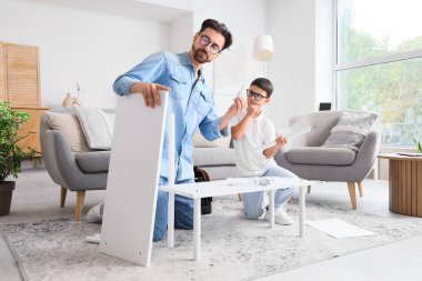 Babam ve düşünceli küçük oğlu evde raf montajı yapıyor.