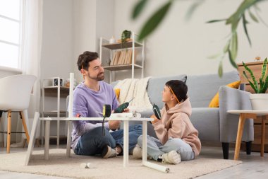 Babası ve küçük oğlu enstrümanları evde monte ediyorlar.