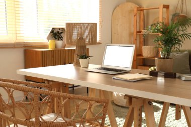 Oturma odasında dizüstü bilgisayarı, lambası ve bitkileri olan programcı masası.