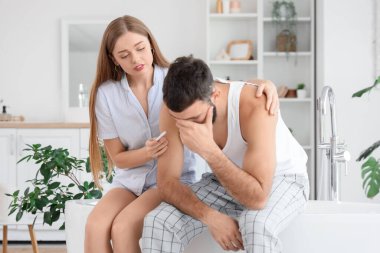 Banyoda hamilelik testi olan üzgün genç bir çift.