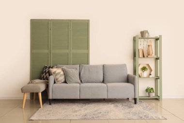 Oturma odasının içinde kanepe, yumuşak bank ve raf ünitesi var.