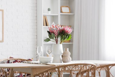 Yemek odasında protea çiçekleri olan masa ayarı