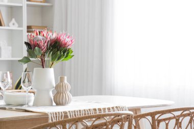 Yemek odasında protea çiçekleri olan masa ayarı