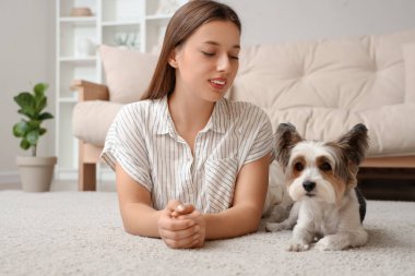 Bisikletli teriyer köpeğiyle evde halıya uzanmış genç bir kadın.