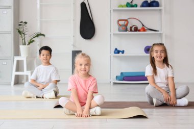 Spor salonundaki minderlerde oturan şirin çocuklar.