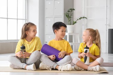 Beden dersinde mindere oturmuş köpük silindirli ve su şişeli şirin çocuklar.