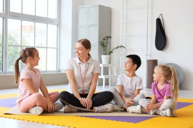 Jimnastik hocasıyla oturan şirin çocuklar.