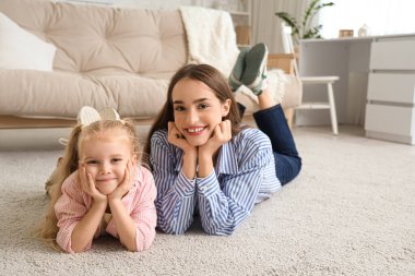 Evde halıya uzanmış küçük tatlı bir kızla dadı.