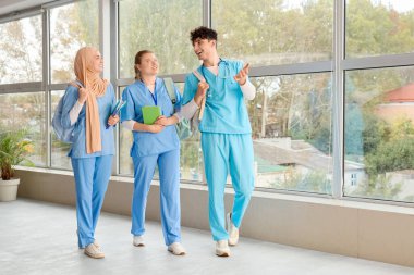 Üniversitenin penceresinin yanında sırt çantaları ve kitapları olan tıp öğrencileri.