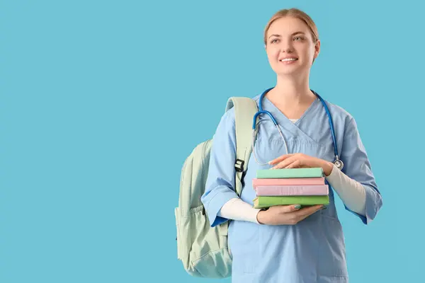 Female medical student with books on blue background