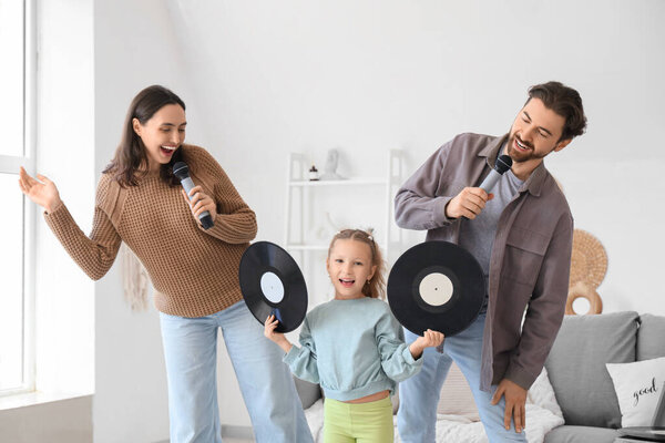 Счастливая семья с микрофонами и виниловыми дисками поет караоке дома