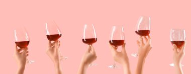 Pembe arka planda kırmızı şarap kadehleri tutan birçok kadın eli var. 